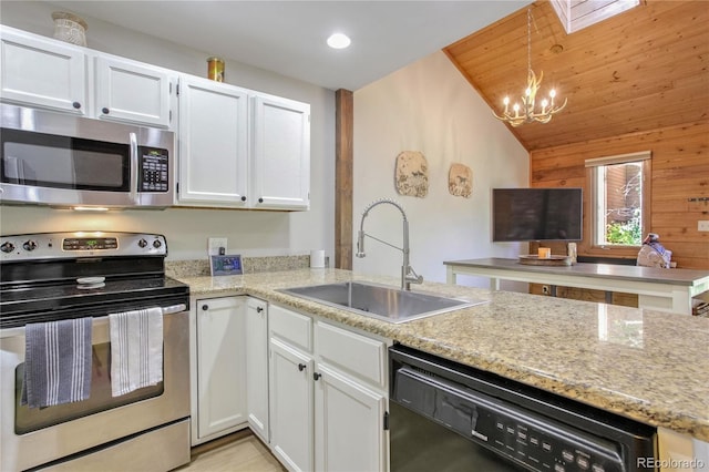 kitchen featuring pendant lighting, sink, a notable chandelier, wooden walls, and appliances with stainless steel finishes