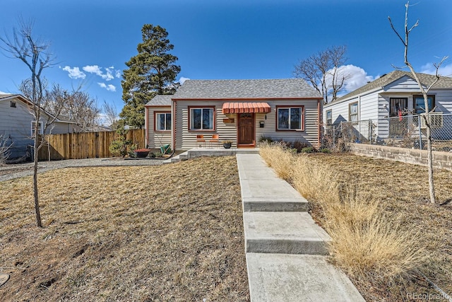 bungalow-style home with a front yard and fence