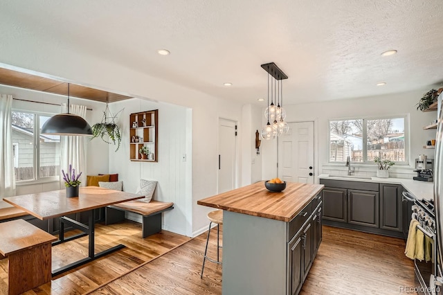 kitchen featuring hanging light fixtures, gray cabinets, a center island, breakfast area, and gas stove