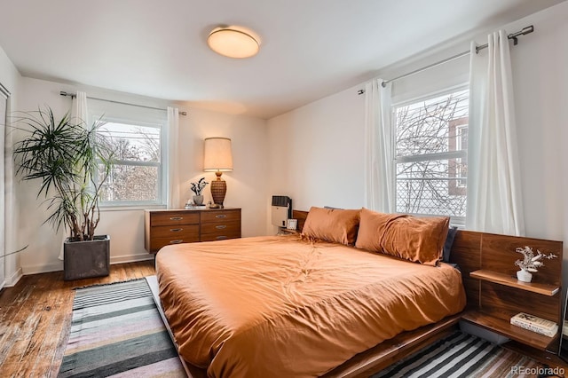 bedroom with baseboards and dark wood-type flooring