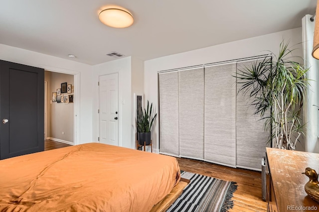 bedroom featuring baseboards, a closet, visible vents, and dark wood-type flooring