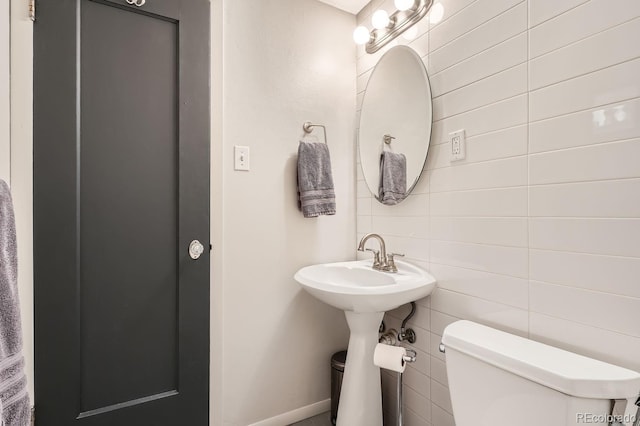 half bathroom with toilet and tile walls