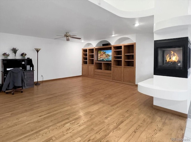 7217 S Zephyr Way, Littleton, CO 80128 - unfurnished living room featuring a multi sided fireplace, light wood finished floors, ceiling fan, and baseboards
