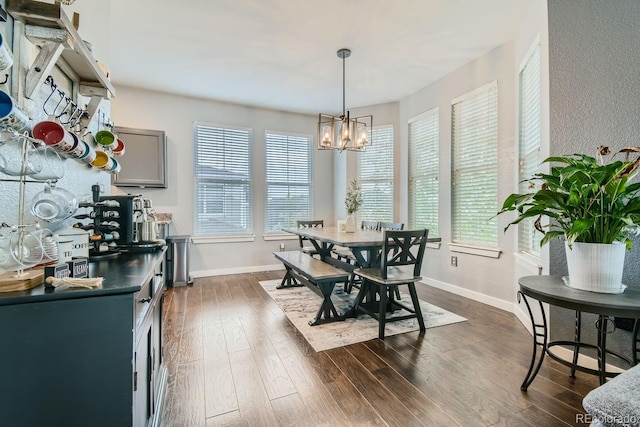 dining room with a notable chandelier, a healthy amount of sunlight, and dark hardwood / wood-style flooring