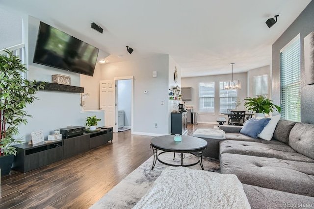 living room with dark hardwood / wood-style flooring, lofted ceiling, and a notable chandelier