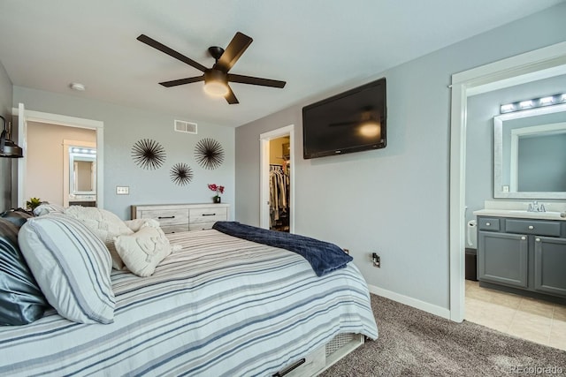 bedroom featuring ceiling fan, a spacious closet, connected bathroom, and a closet