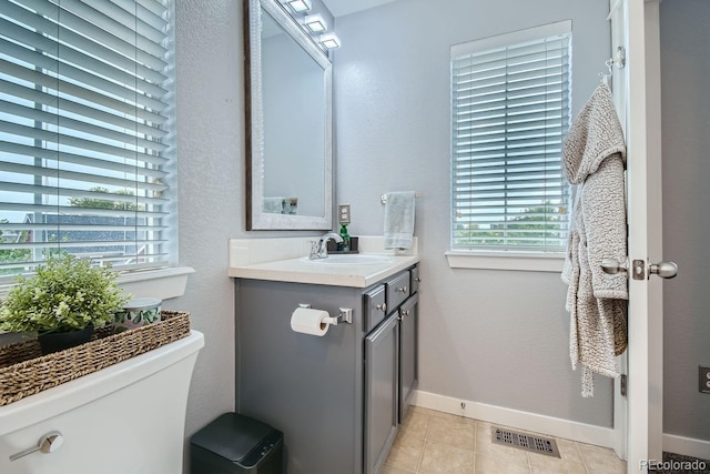 bathroom with toilet, vanity, tile patterned floors, and a wealth of natural light