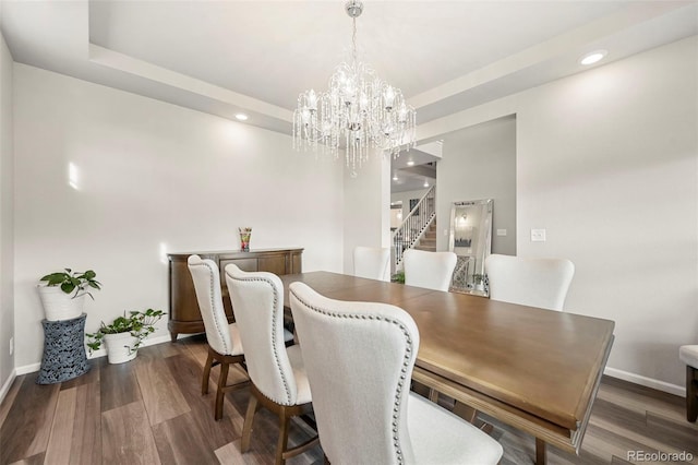 dining area featuring a raised ceiling, dark hardwood / wood-style floors, and a chandelier