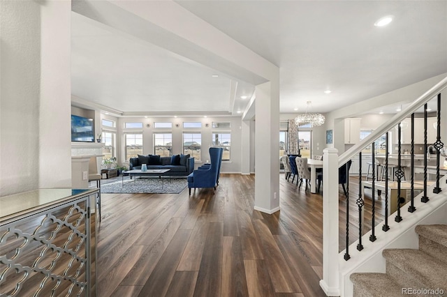 living room with a notable chandelier, wood-type flooring, and a healthy amount of sunlight