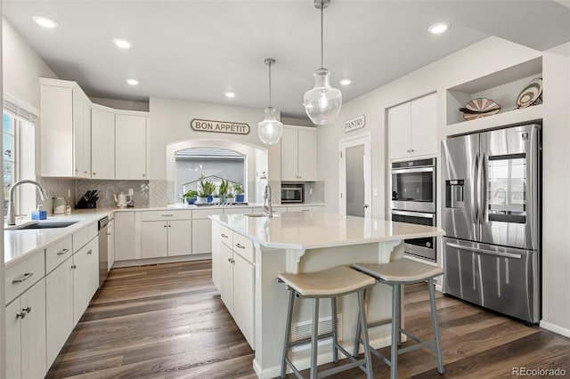 kitchen featuring sink, a kitchen island with sink, stainless steel appliances, white cabinets, and dark hardwood / wood-style flooring