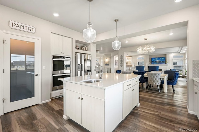 kitchen featuring white cabinetry, sink, hanging light fixtures, a kitchen island with sink, and stainless steel appliances