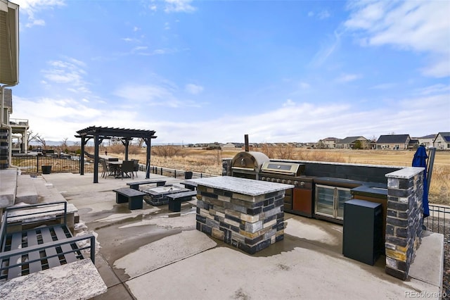 view of patio with a fire pit, an outdoor kitchen, a grill, and a pergola