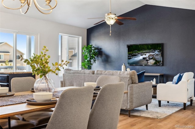 dining area featuring vaulted ceiling, light hardwood / wood-style floors, and a notable chandelier