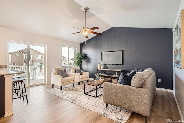 living room with hardwood / wood-style flooring, ceiling fan, and vaulted ceiling