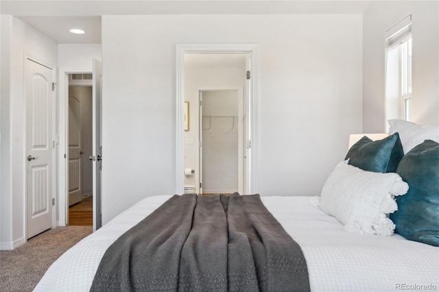 carpeted bedroom featuring a spacious closet and ensuite bathroom