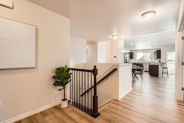 stairs with hardwood / wood-style floors, a notable chandelier, and a textured ceiling