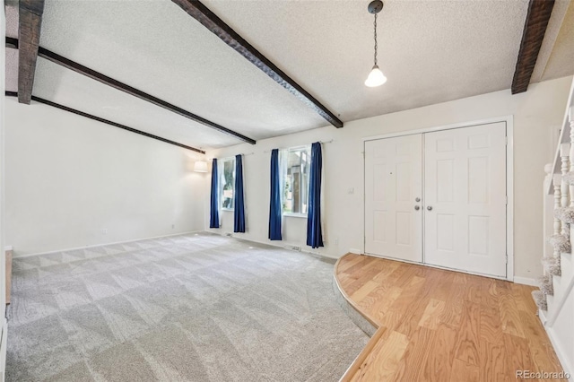 foyer entrance featuring hardwood / wood-style floors, beamed ceiling, and a textured ceiling