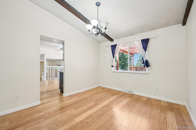 empty room with a textured ceiling, ceiling fan with notable chandelier, lofted ceiling with beams, and light hardwood / wood-style floors