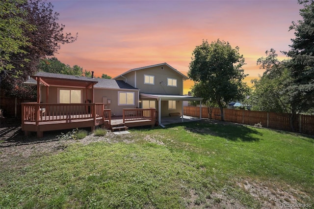 back house at dusk with a lawn and a wooden deck