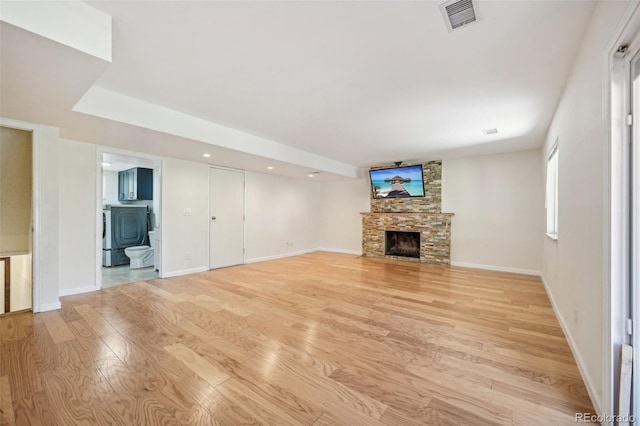 unfurnished living room featuring a stone fireplace and light hardwood / wood-style floors