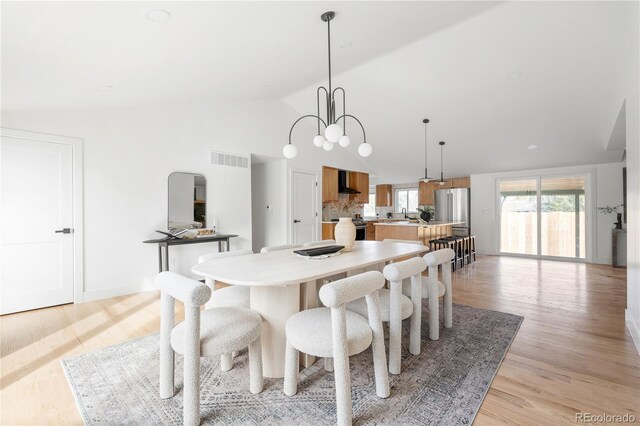 dining room featuring high vaulted ceiling, a notable chandelier, and light wood-type flooring