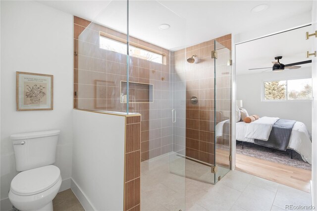 bathroom with a shower with door, plenty of natural light, tile patterned flooring, and toilet