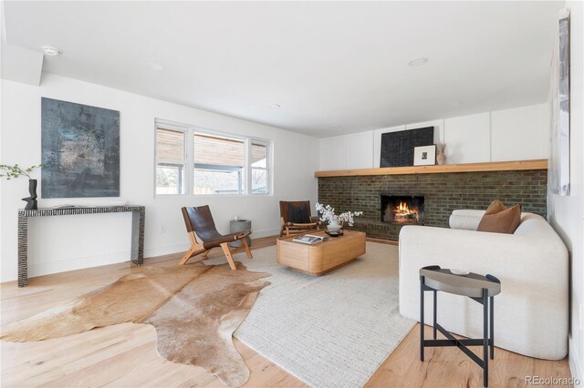 living room with a brick fireplace and light hardwood / wood-style floors