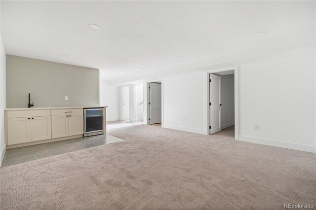 unfurnished living room with light carpet, wine cooler, and indoor wet bar