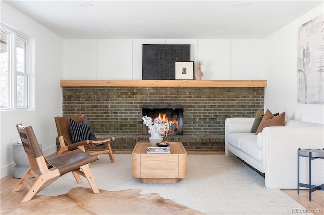 living room featuring a brick fireplace and light hardwood / wood-style flooring