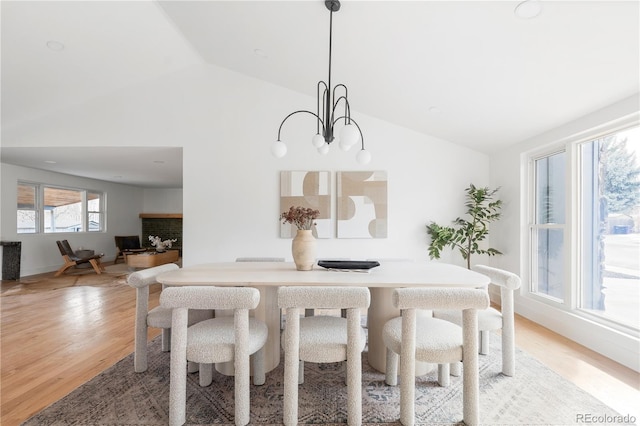 dining space with vaulted ceiling, a notable chandelier, and light wood-type flooring