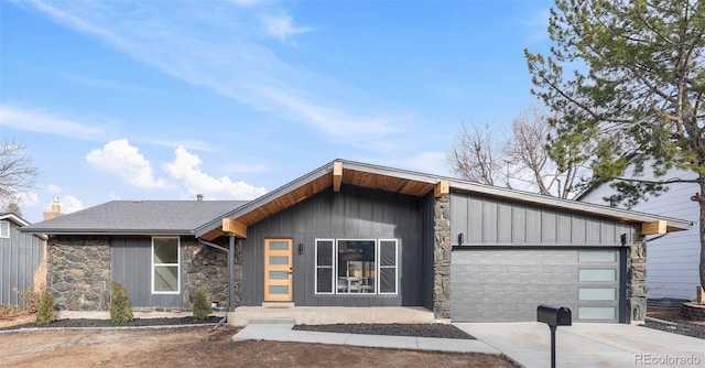 mid-century home featuring an attached garage, stone siding, driveway, board and batten siding, and a chimney