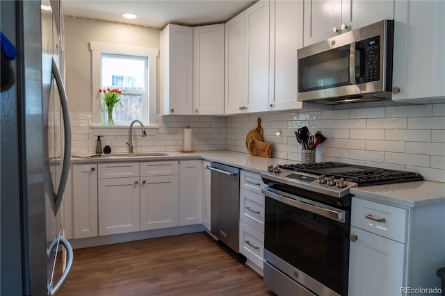 134 S Quitman St, Denver, CO 80219 - kitchen with stainless steel appliances, a sink, white cabinets, decorative backsplash, and light stone counters