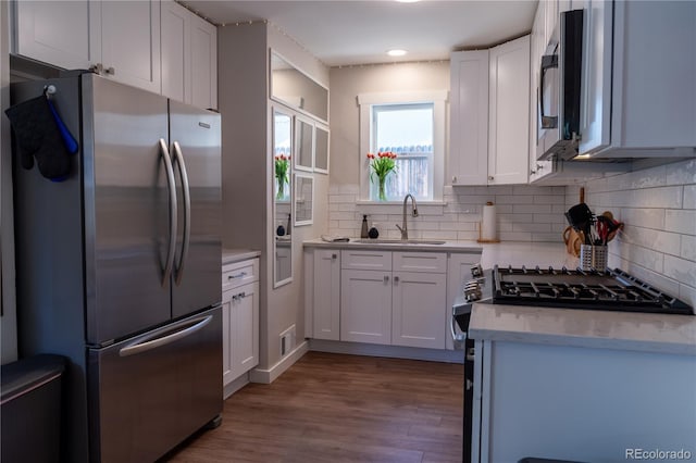 134 S Quitman St, Denver, CO 80219 - kitchen featuring appliances with stainless steel finishes, a sink, backsplash, wood finished floors, and recessed lighting