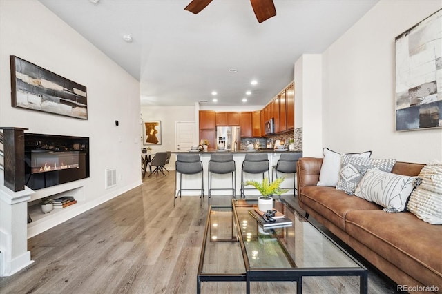 living room with light hardwood / wood-style floors and ceiling fan