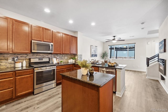 kitchen featuring decorative backsplash, appliances with stainless steel finishes, a center island, and light hardwood / wood-style flooring