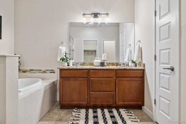 bathroom featuring tile patterned flooring, vanity, and tiled bath