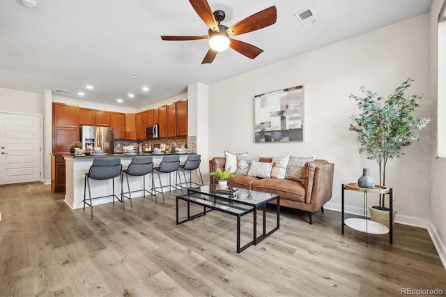 living room featuring ceiling fan and light hardwood / wood-style flooring