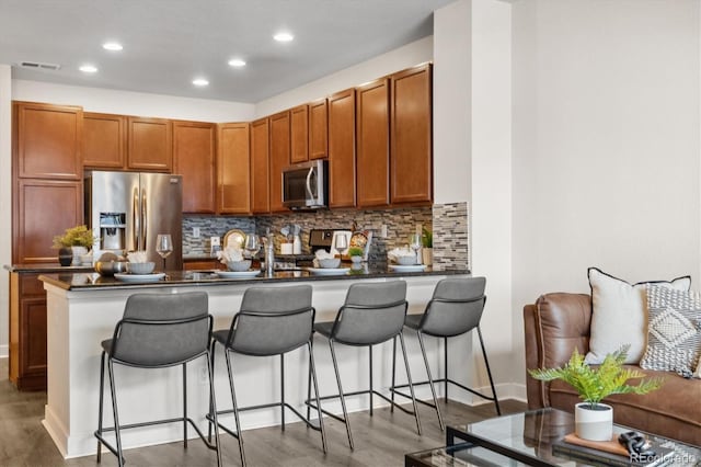 kitchen with a breakfast bar, kitchen peninsula, dark wood-type flooring, and appliances with stainless steel finishes