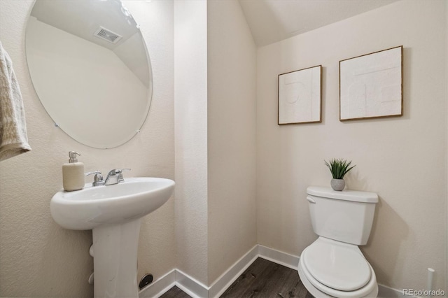 bathroom featuring hardwood / wood-style floors, toilet, sink, and vaulted ceiling