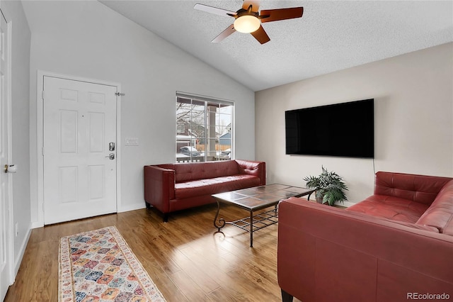 living area with a ceiling fan, lofted ceiling, a textured ceiling, and wood finished floors