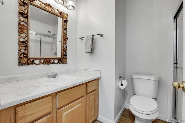 full bath with visible vents, baseboards, toilet, a shower with shower door, and vanity