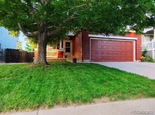 obstructed view of property with a garage, driveway, a front yard, and fence