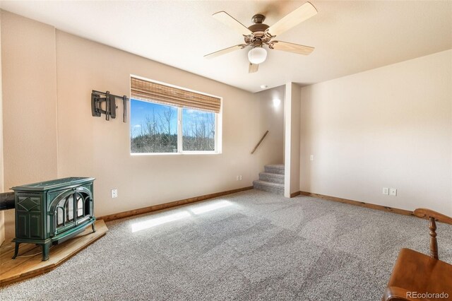 631 County Road 61, Cripple Creek, CO 80813 - unfurnished living room with a wood stove, stairs, carpet floors, ceiling fan, and baseboards