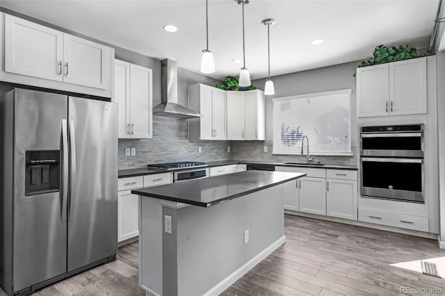 6932 E 133rd Ave, Thornton, CO 80602 - kitchen featuring stainless steel appliances, wall chimney exhaust hood, dark countertops, wood finished floors, and recessed lighting