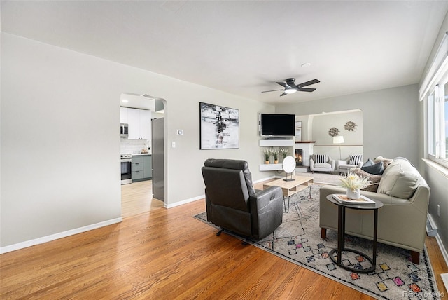 6513 Gray St, Arvada, CO 80003 - living area featuring light wood-style flooring, ceiling fan, and arched walkways