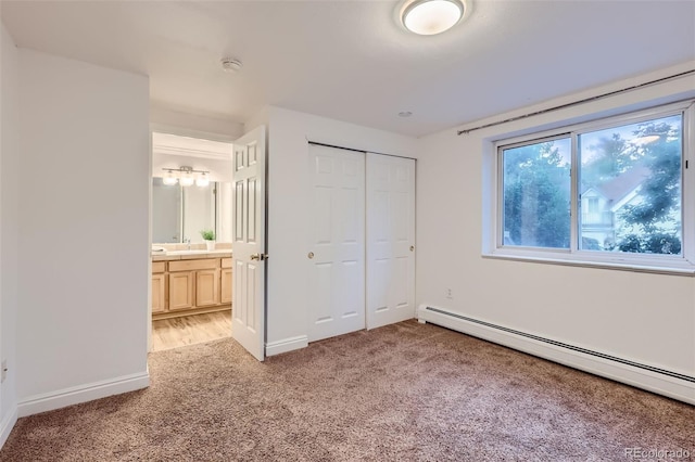 unfurnished bedroom with connected bathroom, light carpet, a closet, and a baseboard radiator