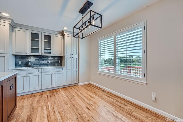9357 Lark Sparrow Dr, Highlands Ranch, CO 80126 - kitchen with light wood-type flooring, baseboards, recessed lighting, decorative backsplash, and glass insert cabinets