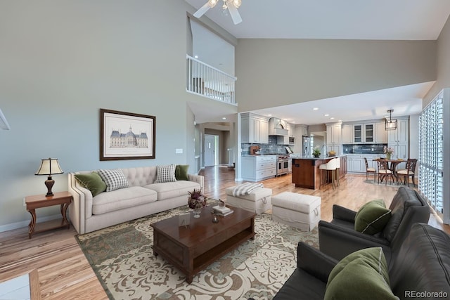 living room with sink, light wood-type flooring, high vaulted ceiling, and ceiling fan