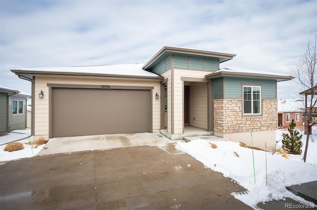 prairie-style house featuring a garage, stone siding, and concrete driveway