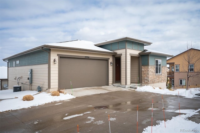 prairie-style house with a garage, stone siding, and driveway